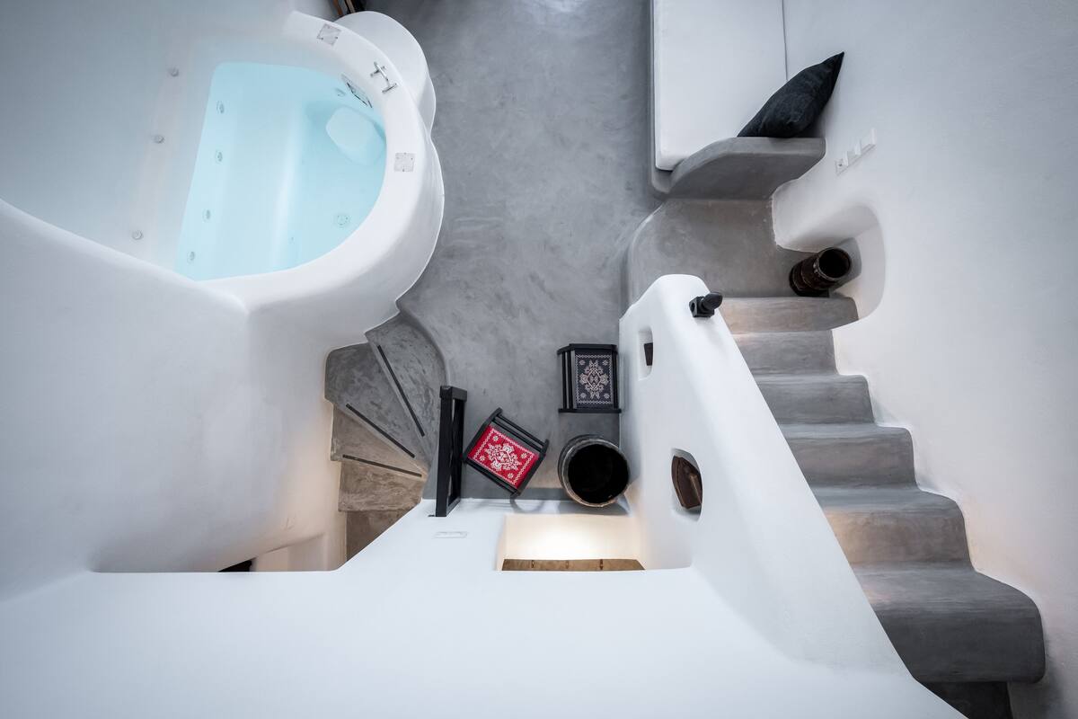 A modern bathroom with a bathtub, a shower, and a staircase.