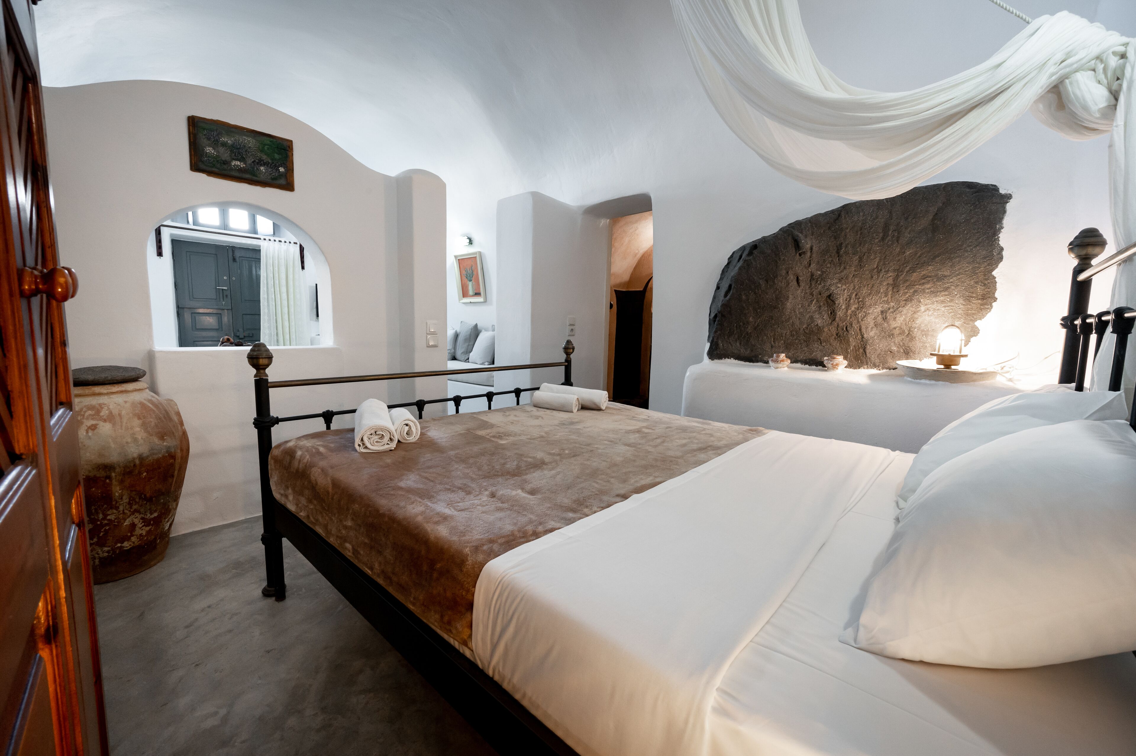 Un dormitorio con cama, una gran formación rocosa y una ventana con cortinas.