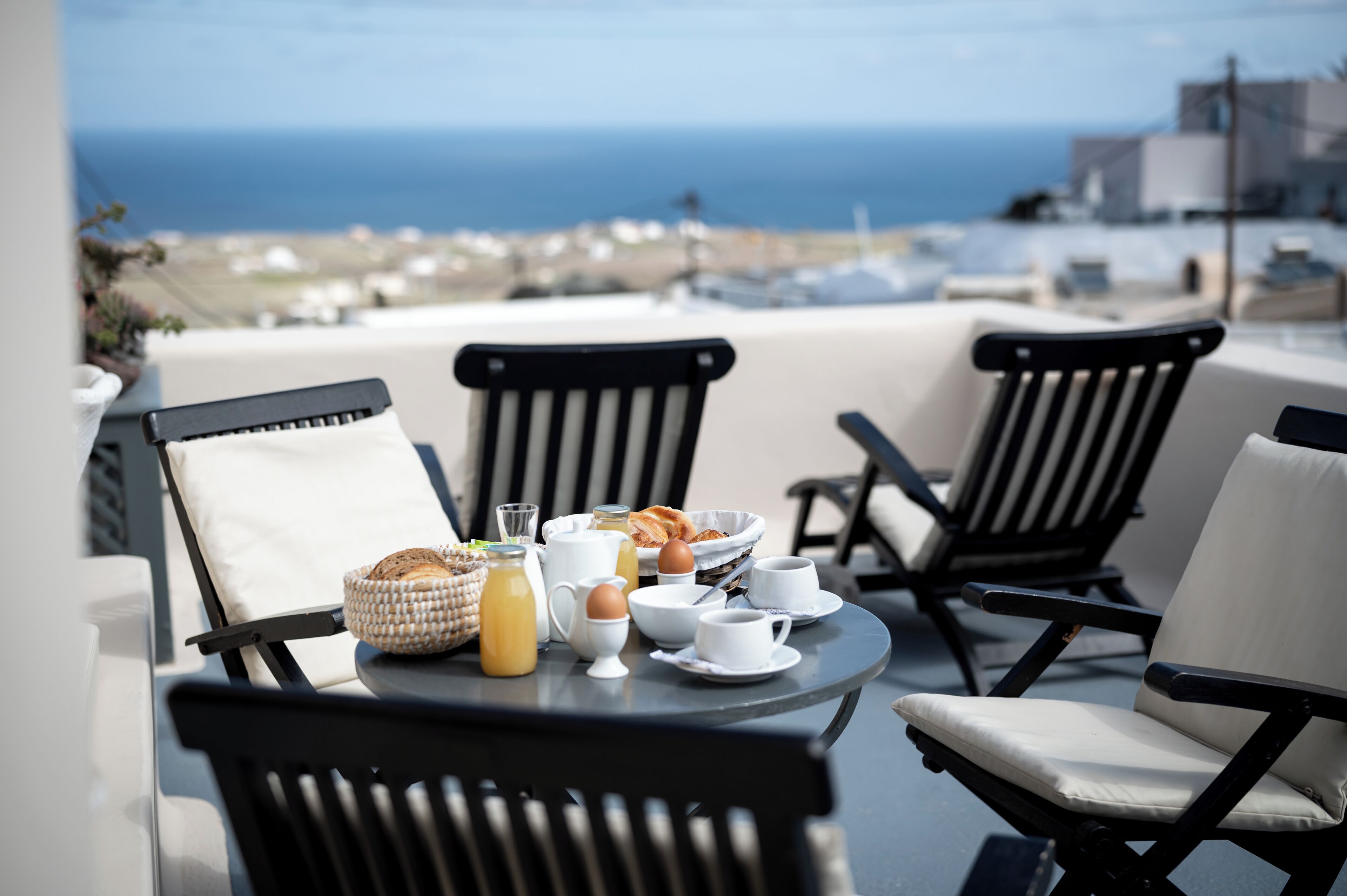 Une table avec des aliments pour le petit-déjeuner et des chaises sur un balcon donnant sur la mer.