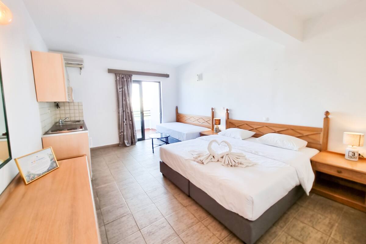 Ein Hotelzimmer mit einem großen Bett, einem Schreibtisch, einem kleinen Tisch und Blick ins Freie.