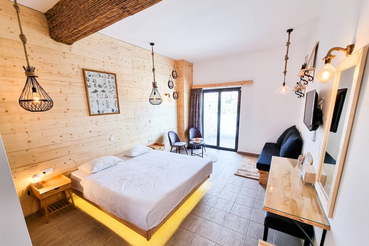 Ein modernes Schlafzimmer mit einem großen Bett, einem Schreibtisch und einem Stuhl. Ein Fenster bietet einen Ausblick nach draußen.