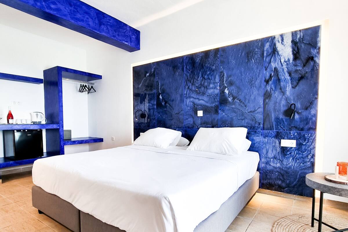 Ein modernes Schlafzimmer mit einem großen Bett, einem eingebauten Schreibtisch und einer blauen Akzentwand.