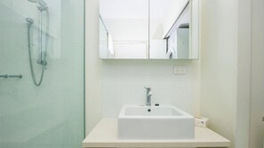 A bathroom with a glass shower enclosure, a white sink, and a mirror above the sink. - 1 Bright Point Apartment 3303 (Nelly Bay)