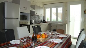Una cucina compatta con elettrodomestici moderni, un tavolo da pranzo per quattro persone e vista all'esterno da una grande finestra.