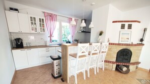 A modern kitchen with white cabinets, a wooden countertop, a built-in stove, and a dining area with white chairs.