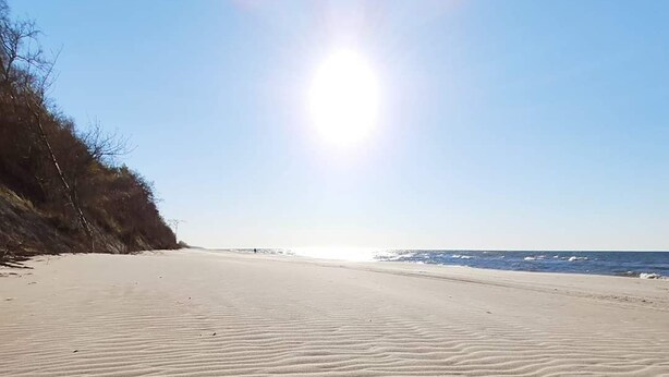 A beach with sand patterns and the words "IN WILLO NORD" written in the sand.