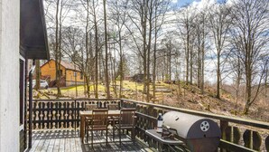Eine Holzterrasse mit Gartenmöbeln und einem Grill.