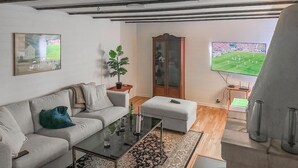 Ein modernes Wohnzimmer mit einer Couch, einem Couchtisch und einem großen Fenster mit Blick auf ein Fußballfeld.