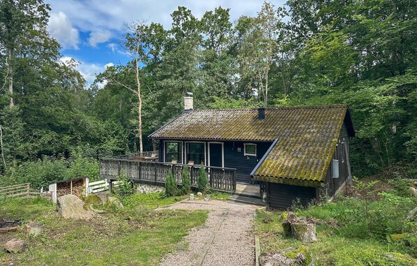 A rustic cabin with a wooden deck, surrounded by dense forest. - 3 bedroom pet friendly home in Hörby (Hörby)