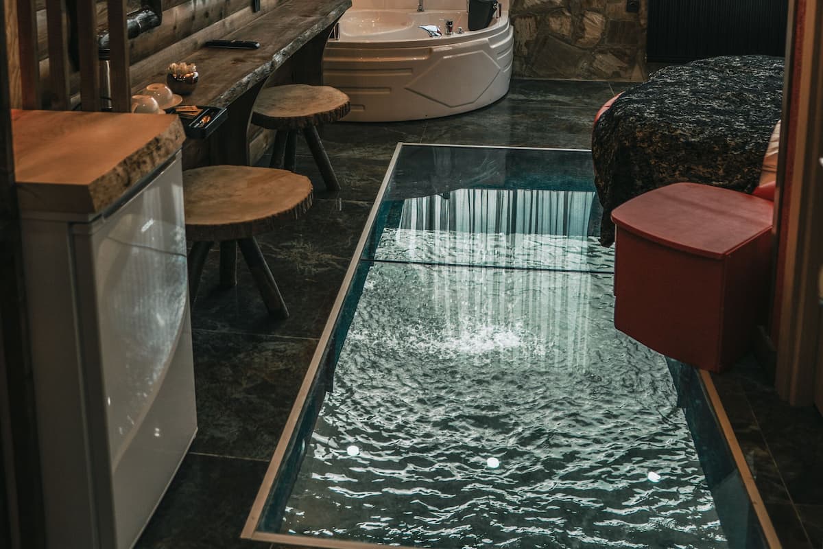 A modern bathroom with a glass-enclosed pool, a large bathtub, and a vanity with a mirror.