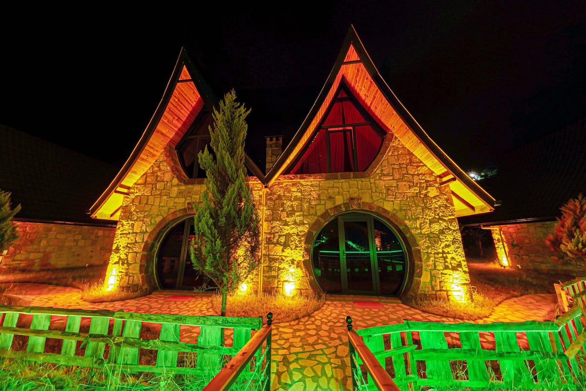 A stone building with a triangular roof and two large arched windows.