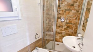 Een badkamer met toilet, bidet, douche en wastafel.