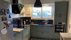 A kitchen with grey cabinets, a black countertop, a sink, and a stove. - Townhome (Lanester)