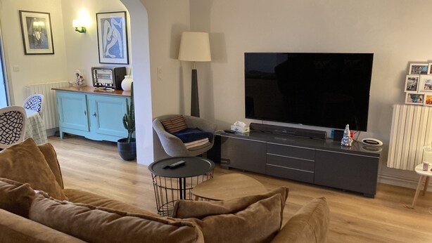 A living room with a sofa, a TV, a lamp, and a small table. - Townhome (Lanester)