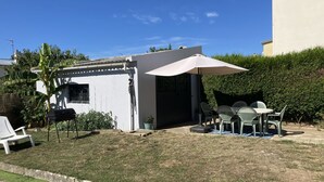 A patio area with a white building, outdoor furniture, and a large umbrella. - Townhome (Lanester)