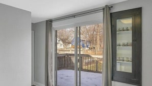 A room with a large sliding glass door leading to a deck, a dark wooden floor, and a built-in cabinet with glass doors.