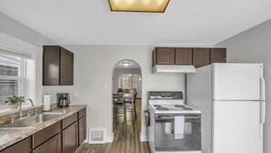 A modern kitchen with a stainless steel range hood, a white refrigerator, and wooden cabinets.