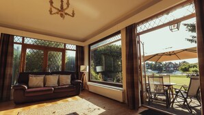 A spacious living room with a large window, a sofa, and a dining area with outdoor seating.