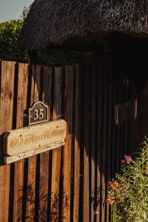 Traditional building with a thatched roof and wooden fence, featuring a designated unit.