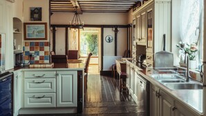 A kitchen with white cabinets, a wooden floor, and a view of the outdoors.
