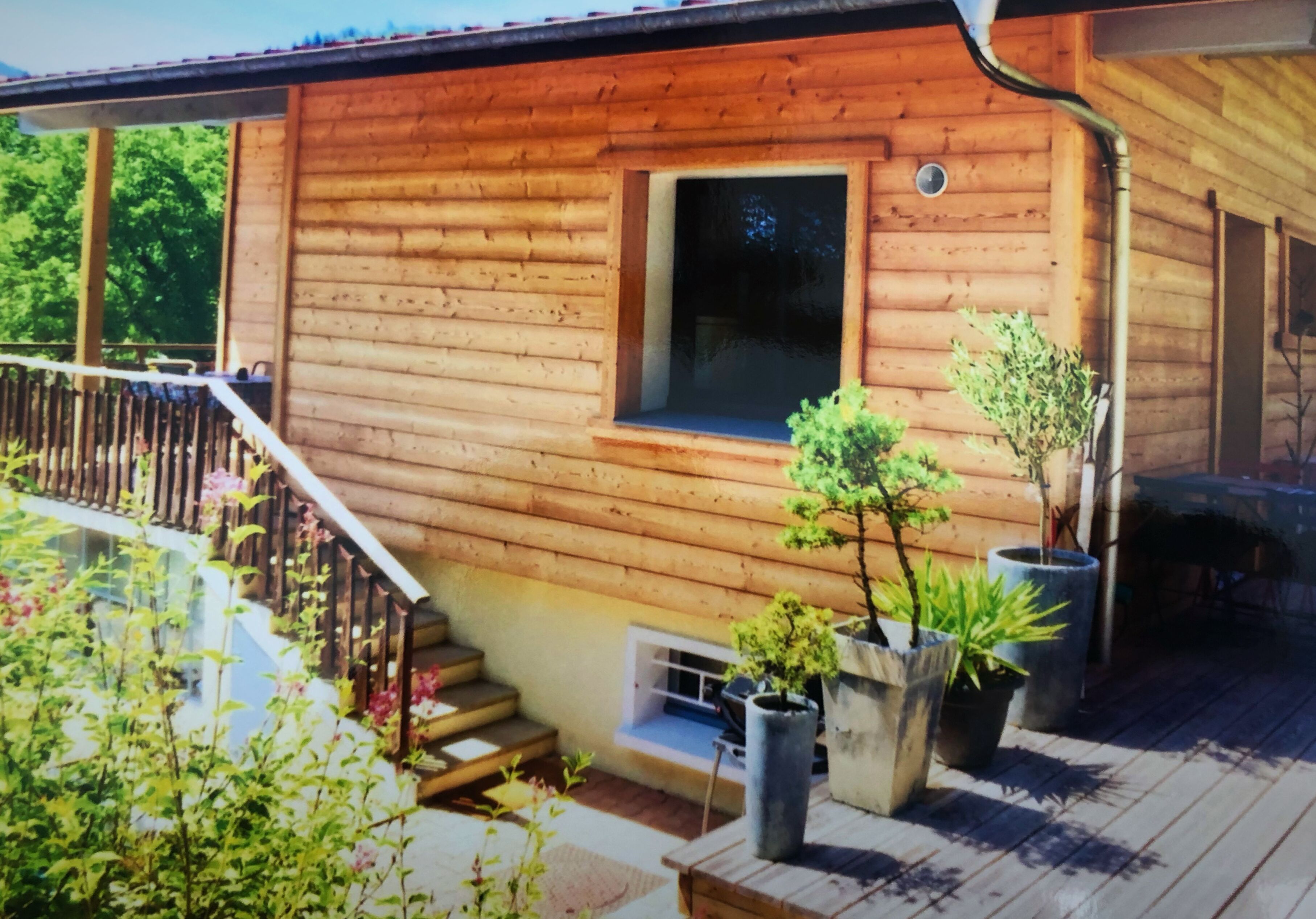 Une cabane en bois dotée d’un balcon, de plantes en pot et d’une fenêtre.