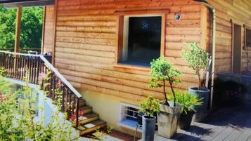 Une cabane en bois dotée d’un balcon, de plantes en pot et d’une fenêtre.