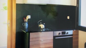 A compact kitchen with a black countertop, wooden cabinets, and a built-in oven. - 3 Bedroom Villa in Dingy-Saint-Clair (Dingy-Saint-Clair)