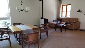 A living room with a wooden dining table, two chairs, a sofa, and a floor lamp. - La petite maison (Wolfgantzen)