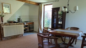 A cozy kitchen with a dining area, featuring a wooden table, chairs, and a radiator. - La petite maison (Wolfgantzen)