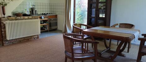 A cozy kitchen with a dining area, featuring a wooden table, chairs, and a radiator.