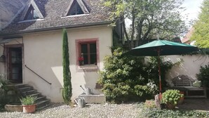 A house with a sloped roof, a small window with a red frame, a door, and a staircase leading to the entrance. - La petite maison (Wolfgantzen)