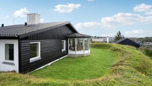 Una casa moderna con fachada negra, un amplio ventanal de vidrio y un césped bien cuidado.