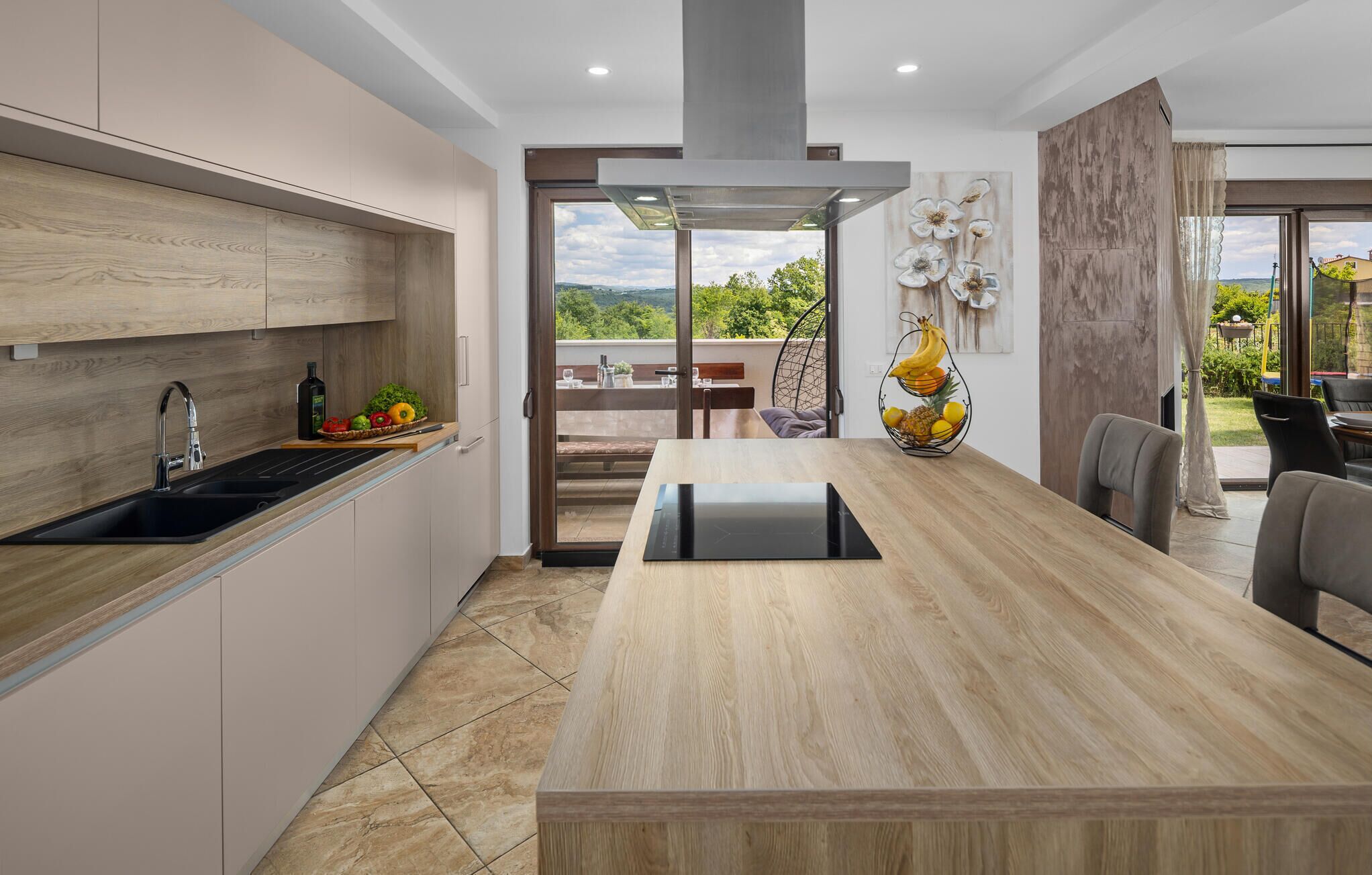 A modern kitchen with a wooden countertop, a built-in stove, and a dining area with a table and chairs.