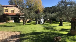 A stone building with a tiled roof and a grassy yard with trees. - Finca vergel ****.HABITACIONES. bed and breakfast.  SIERRA DE GATA (sierra de gata)