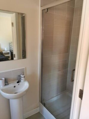 Ein Badezimmer mit weißem Waschbecken, Spiegel und Duschkabine.