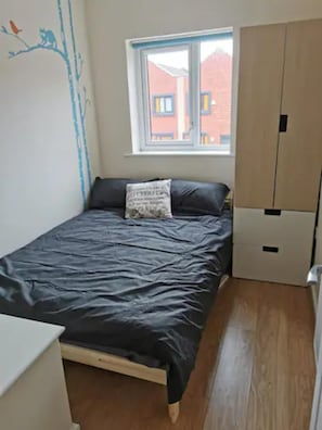 Un dormitorio con cama, ventana y armario.