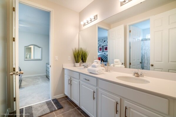 A modern bathroom with a double sink vanity, a large mirror, and a potted plant.