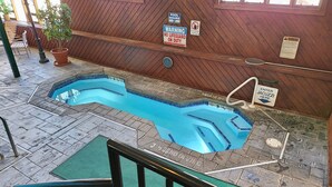 A pool area with a wooden deck, a diving board, and a sign indicating 'No Lifeguard on Duty'.