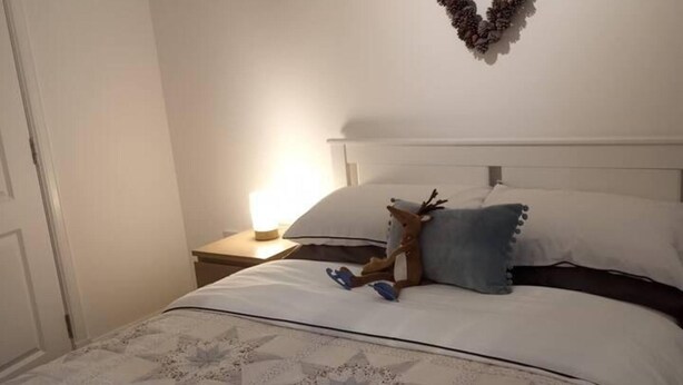 A neatly made bed with a star-patterned bedspread, a pillow, and a stuffed reindeer toy.