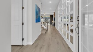 A hallway with a staircase, white walls, and a blue abstract painting.