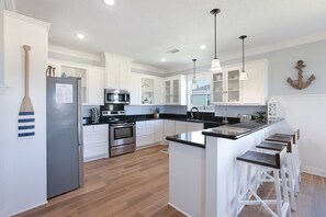 A modern kitchen with white cabinets, stainless steel appliances, and a wooden island with bar stools.