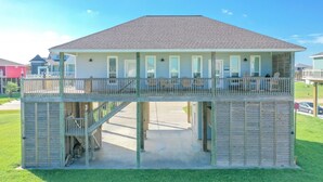 A two-story house with a balcony, a covered porch, and a staircase leading to the upper level. - Everleigh After 3 Bedroom Home by RedAwning (Port Bolivar)