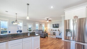 A spacious kitchen with white cabinetry, a large stainless steel refrigerator, and a central island. - Everleigh After 3 Bedroom Home by RedAwning (Port Bolivar)