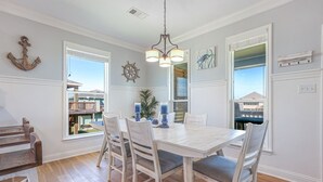 A dining room with a white table and chairs, a chandelier, and nautical decor. - Everleigh After 3 Bedroom Home by RedAwning (Port Bolivar)