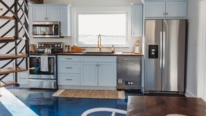 A modern kitchen with white cabinets, stainless steel appliances, and a large window. - Stunning Guesthouse in historic Georgetown w/hot tub! (Georgetown)
