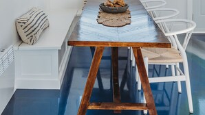 A dining area with a wooden table, white chairs, and a hanging light fixture. - Stunning Guesthouse in historic Georgetown w/hot tub! (Georgetown)