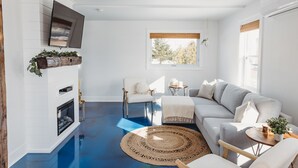 A modern living room with a fireplace, a large window, and a blue floor. - Stunning Guesthouse in historic Georgetown w/hot tub! (Georgetown)