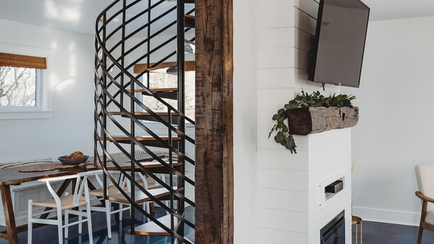 A modern living room with a spiral staircase, a flat-screen TV mounted on a white wall, and a blue floor. - Stunning Guesthouse in historic Georgetown w/hot tub! (Georgetown)