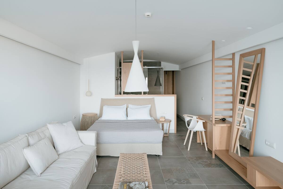 Un dormitorio moderno con cama, sofá, escritorio y armario.