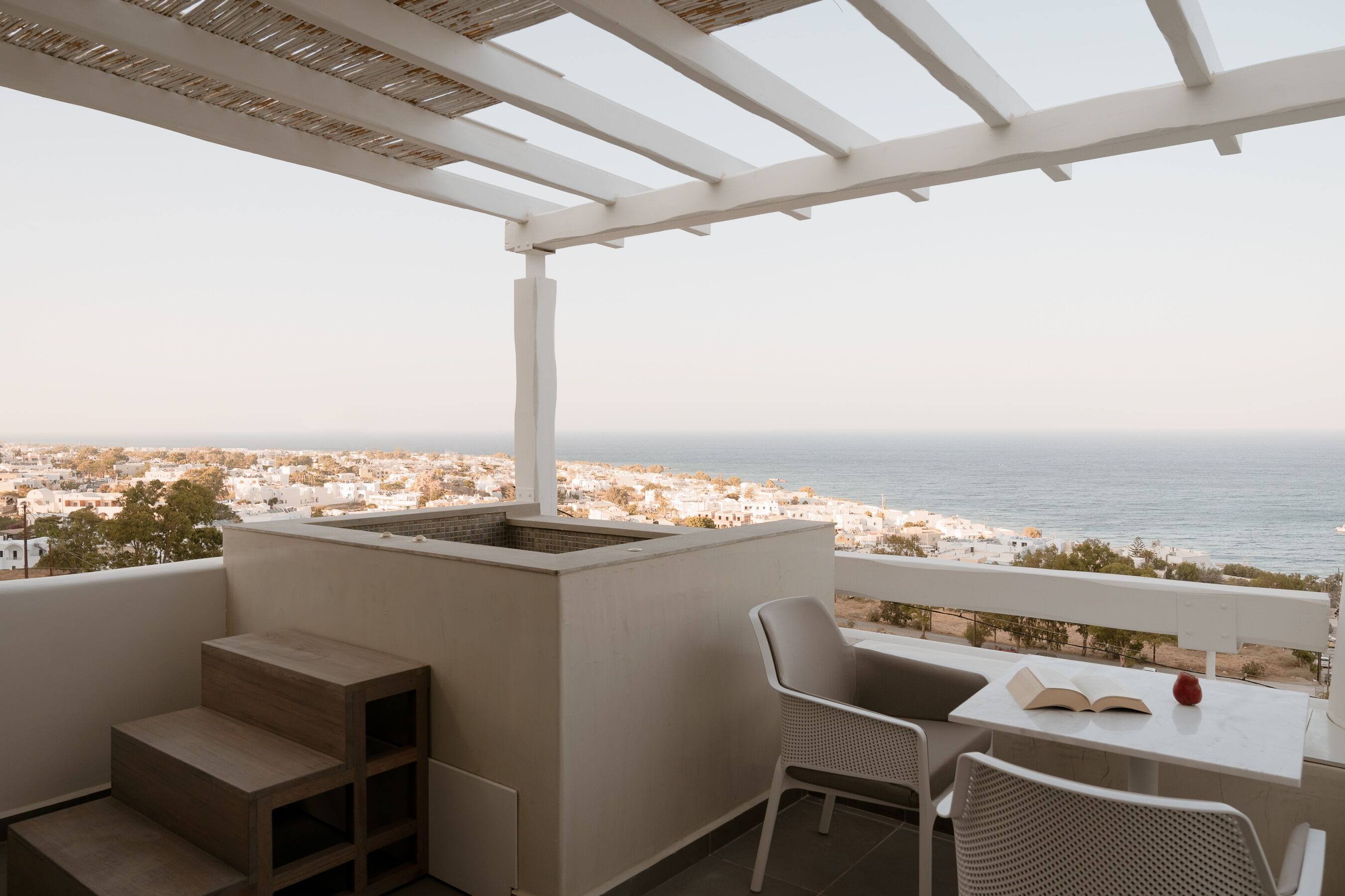 A balcony with a white table, two chairs, and a book.